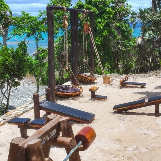 Open-air resort fitness center with exercise equipment overlooking the Caribbean Sea