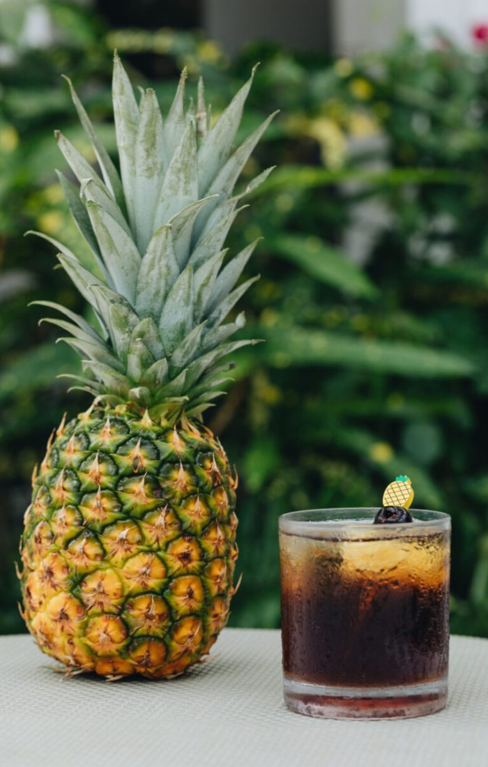 A pineapple next to a cocktail